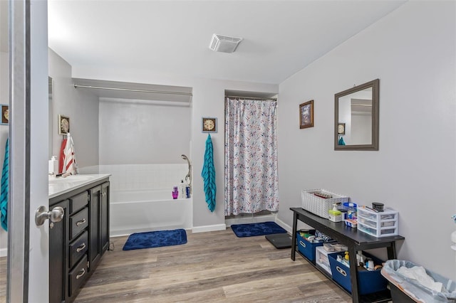 full bathroom with a garden tub, wood finished floors, vanity, visible vents, and baseboards