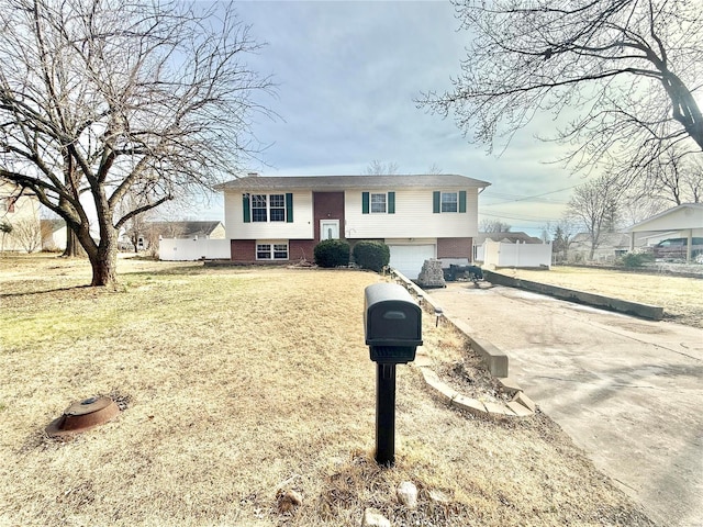 split foyer home with a garage, concrete driveway, brick siding, and a front lawn