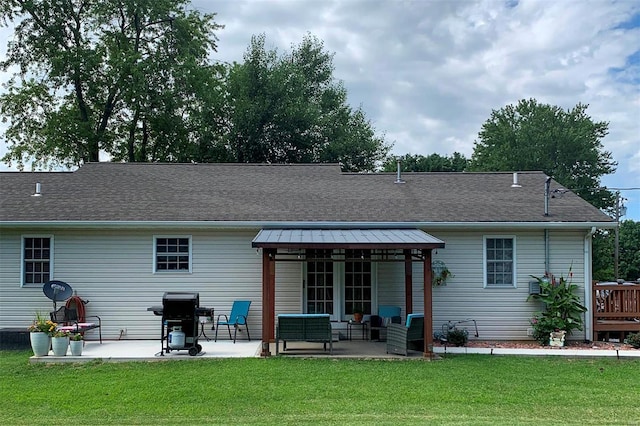 back of property with a patio area, a shingled roof, and a yard