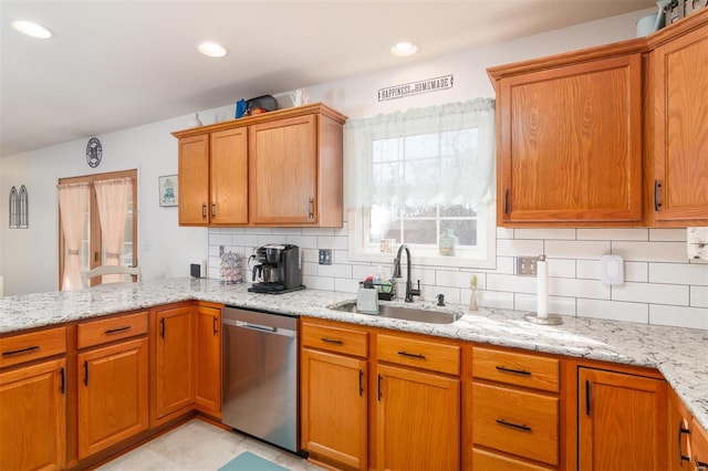 kitchen with a sink, light stone countertops, and stainless steel dishwasher