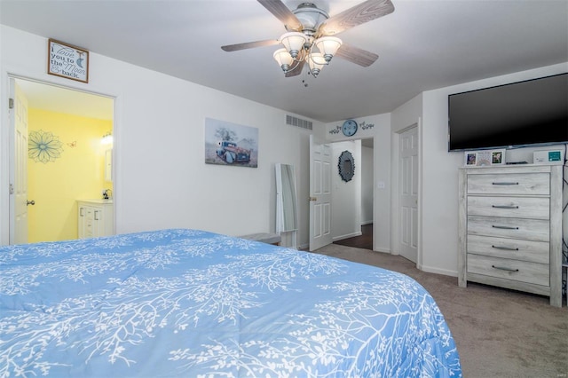 carpeted bedroom featuring a ceiling fan, baseboards, visible vents, and connected bathroom