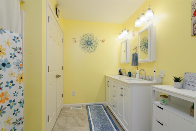 bathroom with double vanity, baseboards, visible vents, and a sink