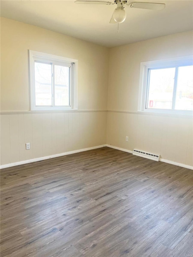 spare room with ceiling fan, wood finished floors, and wainscoting