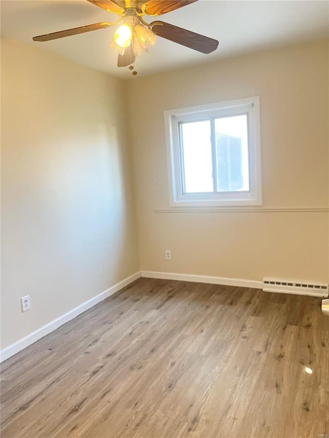 unfurnished room featuring a baseboard radiator, ceiling fan, baseboards, and wood finished floors