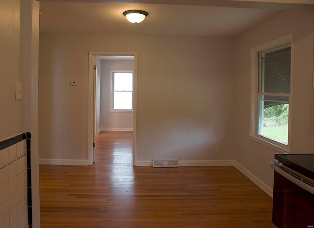 unfurnished room with visible vents, wood finished floors, and baseboards