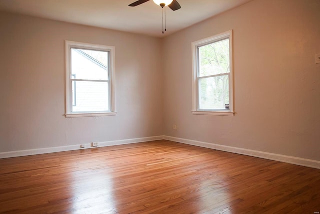 spare room featuring light wood finished floors, baseboards, a wealth of natural light, and ceiling fan