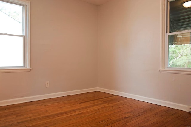 spare room with baseboards and hardwood / wood-style floors