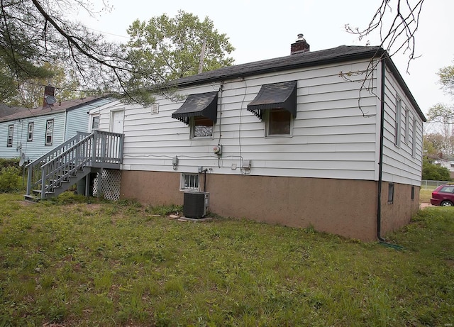 view of side of property with a yard, a chimney, and central AC