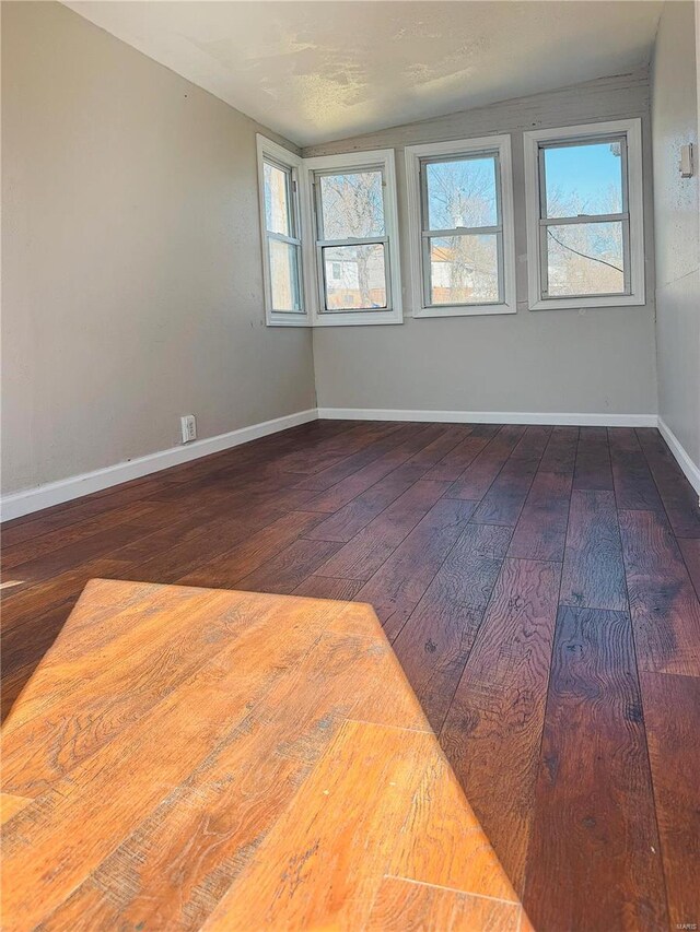 spare room with baseboards and wood-type flooring