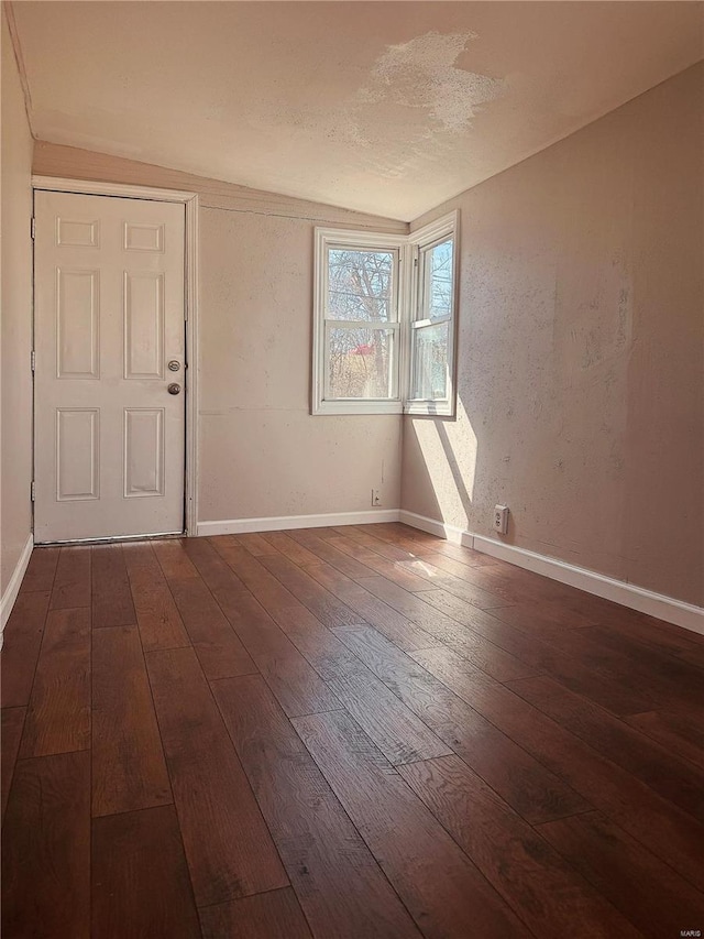 spare room featuring dark wood-style floors and baseboards