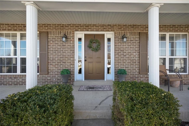 property entrance featuring brick siding and covered porch