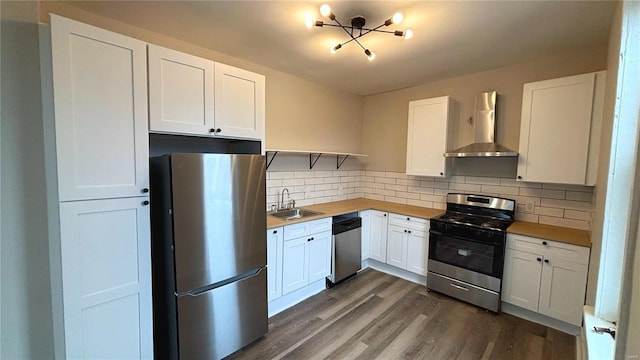 kitchen with tasteful backsplash, wall chimney range hood, dark wood finished floors, stainless steel appliances, and a sink