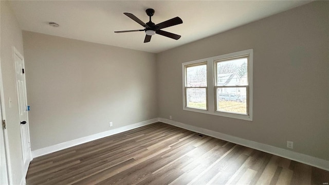 empty room featuring ceiling fan, baseboards, and dark wood finished floors