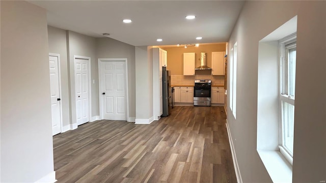 kitchen with tasteful backsplash, dark wood-type flooring, baseboards, wall chimney range hood, and stainless steel appliances