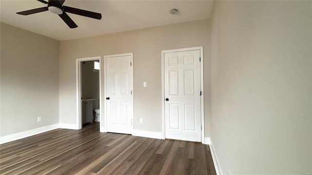 unfurnished bedroom with a ceiling fan, ensuite bathroom, baseboards, and dark wood-style flooring