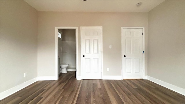 unfurnished bedroom with connected bathroom, baseboards, and wood finished floors