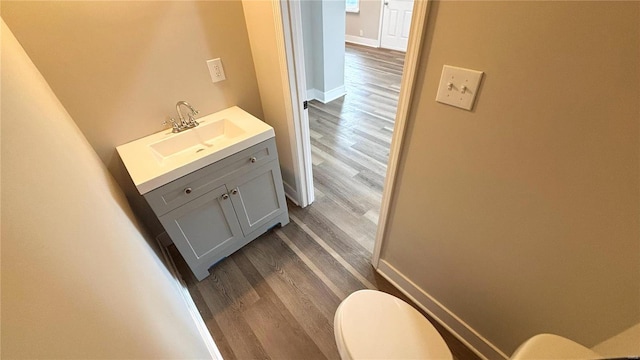 bathroom with baseboards, toilet, wood finished floors, and vanity