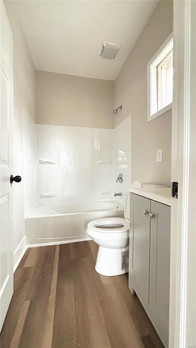 bathroom with vanity, toilet, wood finished floors, and shower / bath combination