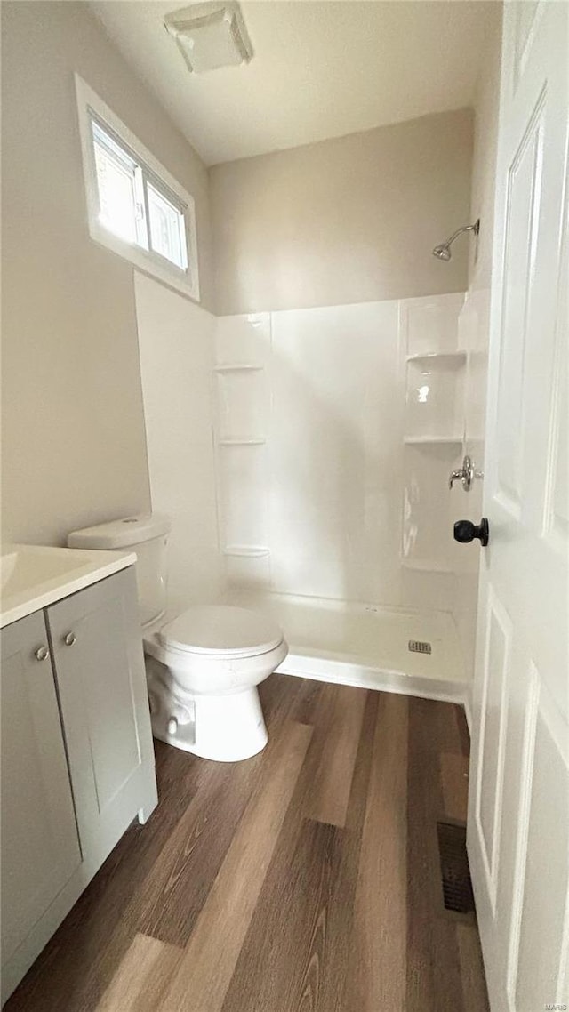 bathroom featuring visible vents, walk in shower, toilet, wood finished floors, and vanity