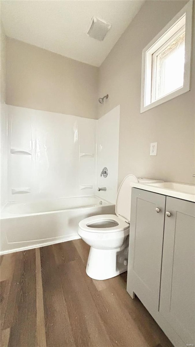 bathroom featuring vanity, wood finished floors, visible vents, shower / bath combination, and toilet