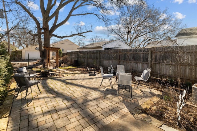 view of patio featuring an outbuilding, a fenced backyard, and a fire pit