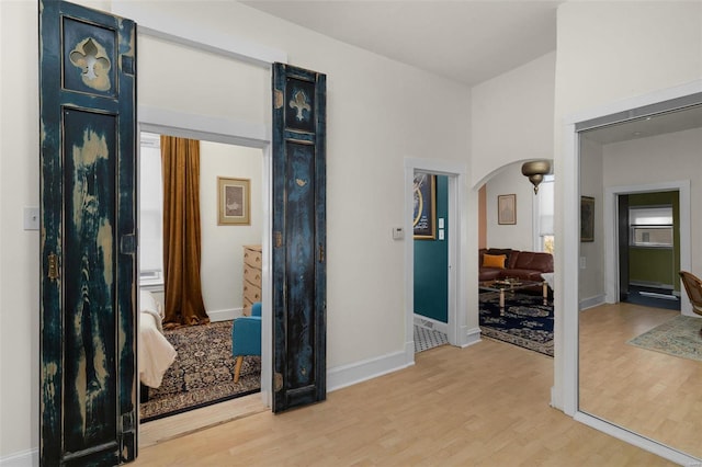 hallway featuring arched walkways, baseboards, and wood finished floors