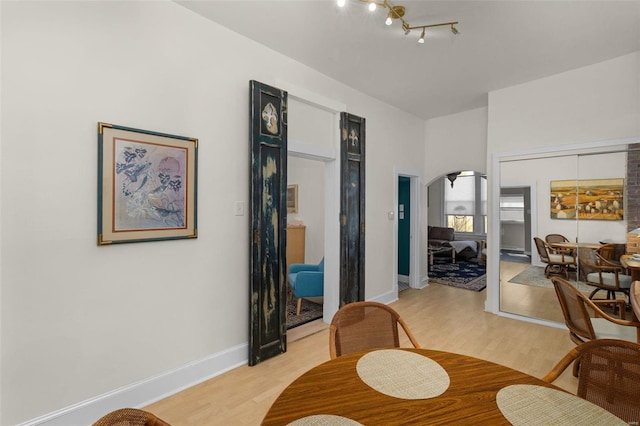 living room featuring arched walkways, light wood finished floors, and baseboards