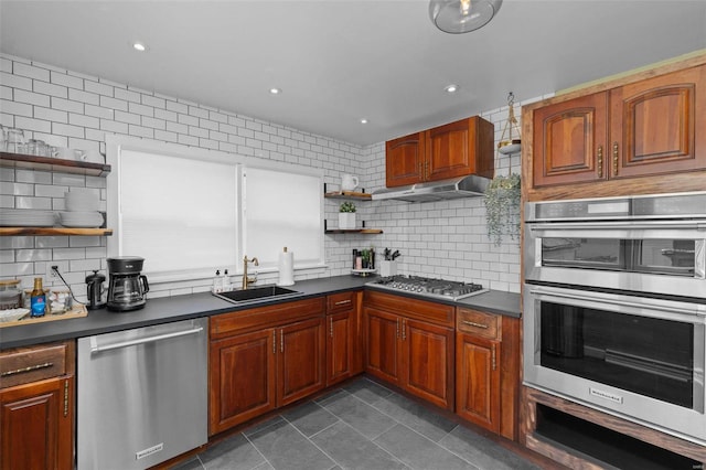 kitchen with dark countertops, stainless steel appliances, under cabinet range hood, open shelves, and a sink