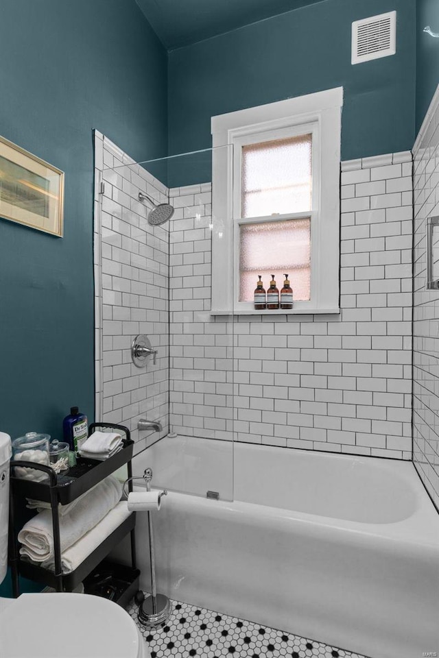 bathroom featuring toilet, shower / bathtub combination, and visible vents