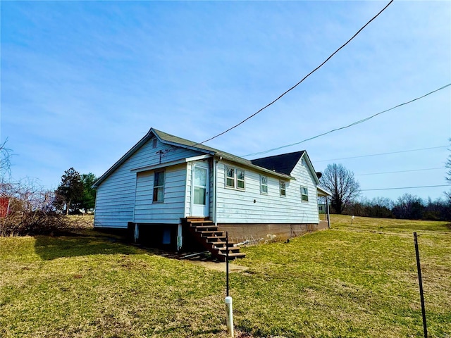 view of side of home with entry steps and a lawn