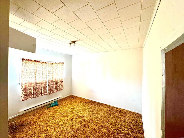 carpeted spare room with a baseboard heating unit