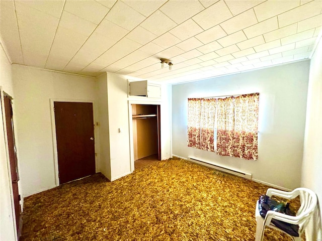 unfurnished bedroom featuring a baseboard heating unit, a closet, and carpet