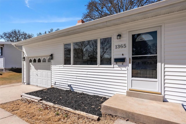 doorway to property featuring an attached garage and driveway