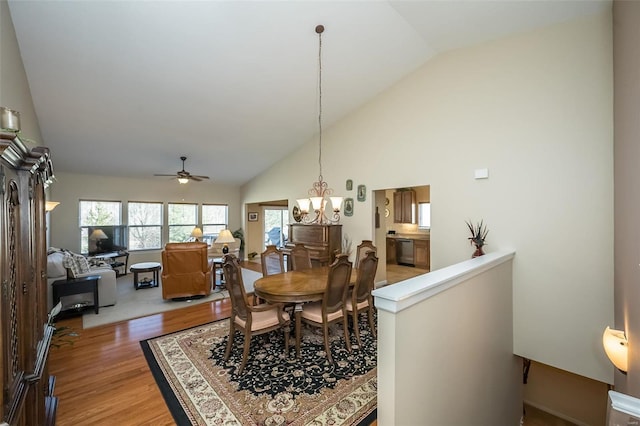 dining area featuring ceiling fan with notable chandelier, light wood-type flooring, and high vaulted ceiling