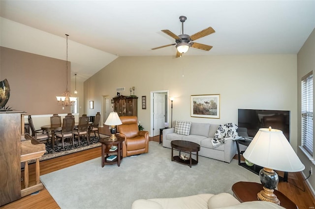 living area with ceiling fan with notable chandelier, lofted ceiling, and wood finished floors