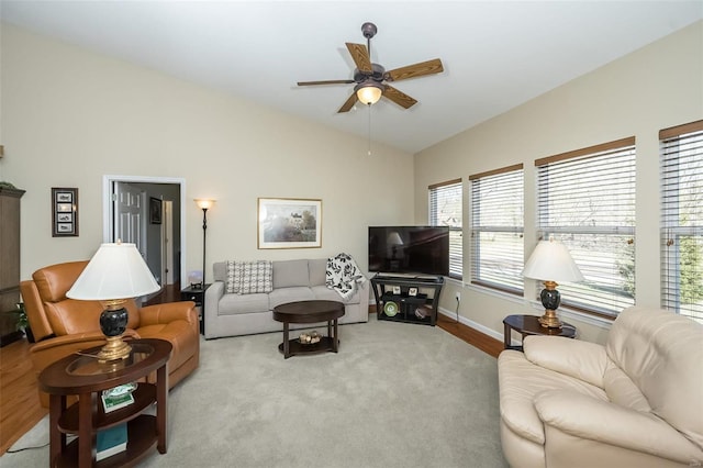 living area with baseboards, a ceiling fan, and vaulted ceiling