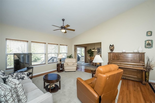 living area with baseboards, lofted ceiling, wood finished floors, and a ceiling fan