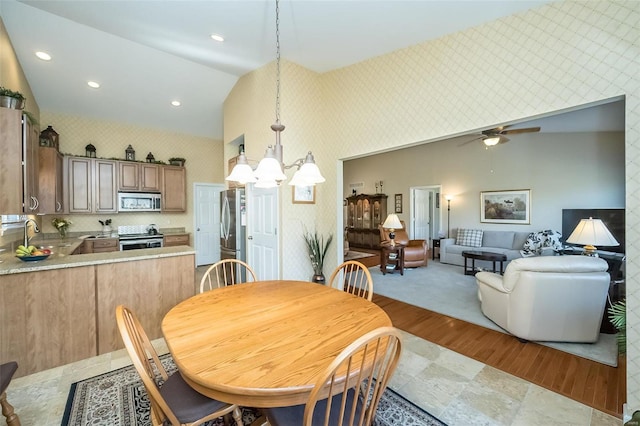 dining area featuring wallpapered walls, recessed lighting, ceiling fan with notable chandelier, and high vaulted ceiling