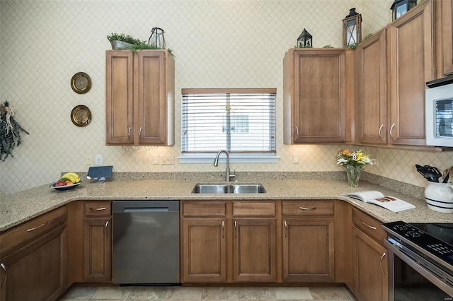 kitchen with light stone counters, backsplash, appliances with stainless steel finishes, and a sink