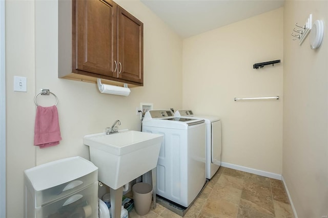 clothes washing area with a sink, cabinet space, baseboards, and washing machine and clothes dryer