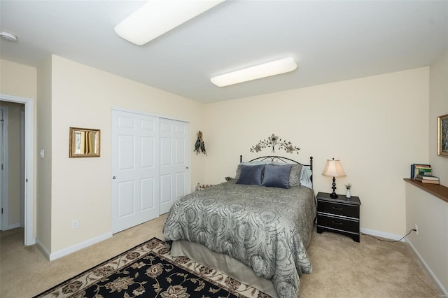 bedroom featuring baseboards, light carpet, and a closet