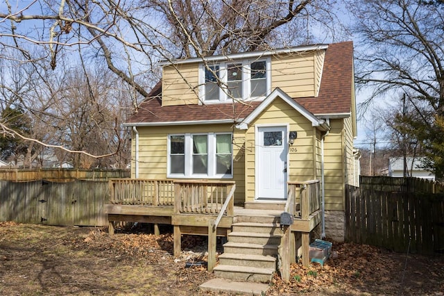 view of front of house with a shingled roof, fence, and a wooden deck