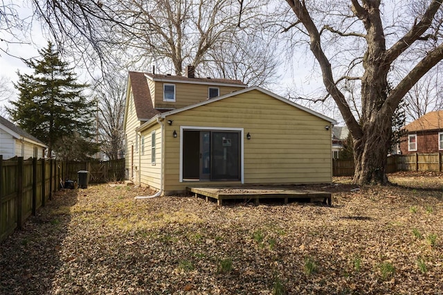 back of house with a fenced backyard and roof with shingles