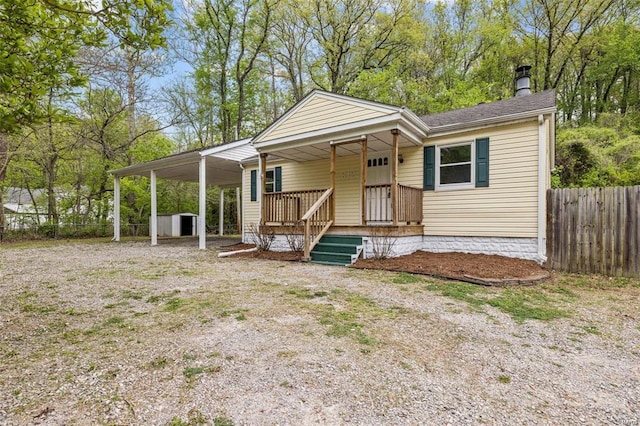 view of front of home with driveway, an attached carport, a porch, and fence