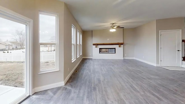 unfurnished living room with a ceiling fan, wood finished floors, a fireplace, and baseboards