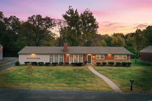 ranch-style house with brick siding, a chimney, and a front yard