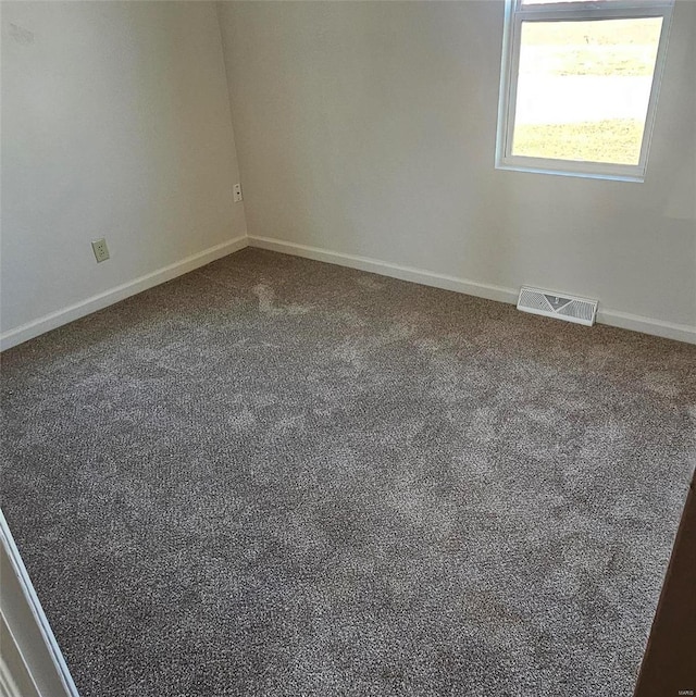 spare room with carpet floors, visible vents, and baseboards