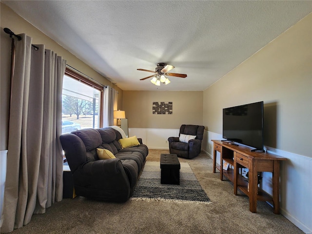 living area featuring carpet flooring, ceiling fan, and a textured ceiling