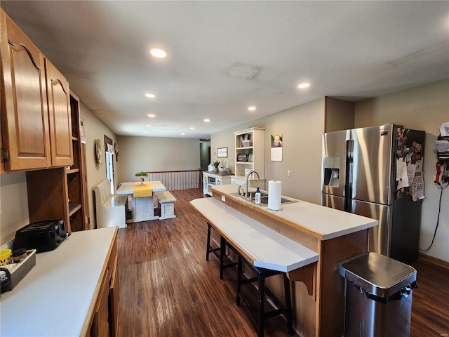 kitchen featuring an island with sink, stainless steel fridge, dark wood-type flooring, and a sink