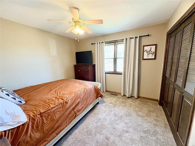 bedroom featuring light colored carpet, a ceiling fan, baseboards, visible vents, and a closet